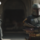 Fennec Shand and Boba Fett stand in front of the blown-up ruins of Garsa Fwip's Sanctuary.